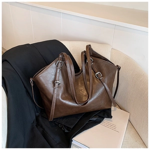 Detail shot of a dark brown large tote bag with silver metal buckle on white sofa