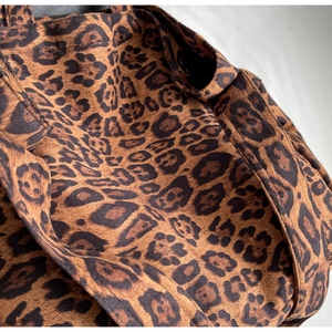 Detailed macro view of the leopard print fabric texture and stitching on the tote bag