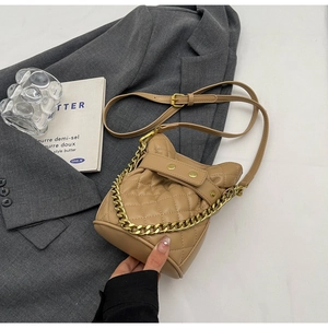 Close-up of quilted pattern bucket bag with golden chain handle and metal studs