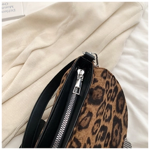 Detail of silver zipper hardware and leopard print textured fabric on a crossbody bag