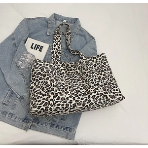 Close-up of leopard print canvas tote bag styled with denim jacket and fashion props