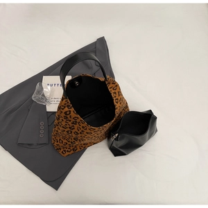 Vue à plat du sac cabas léopard avec une pochette intérieure en cuir noir sur lit blanc