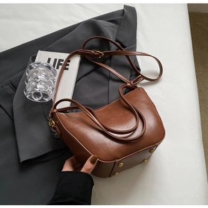Detail view of brown vintage bucket bag with golden metal rivets on the bottom