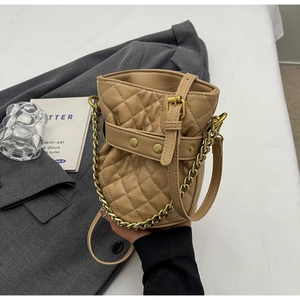 Detailed view of quilted camel bucket bag with golden chain and adjustable strap