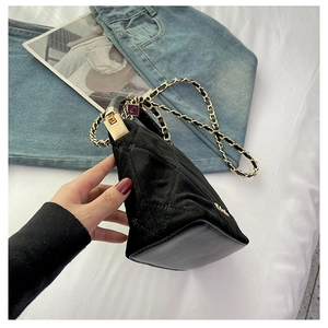 Detail of black quilted velvet crossbody bag with golden chain and diamond stitch pattern