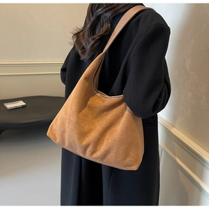 Gros plan d'un sac à bandoulière en daim marron avec sangle en cuir sur un modèle