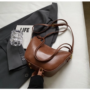 Detail view of brown vintage bucket bag with retro metal rivets and adjustable strap