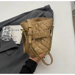 Macro detail of khaki quilted bucket bag with gold chain handle and studded strap