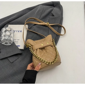 Detailed view of light brown quilted bucket bag with gold chain strap and leather finish