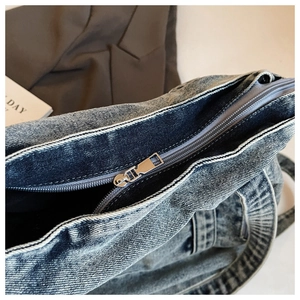 Detailed close-up of premium washed denim tote bag with silver metal zipper and texture
