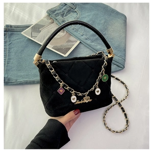 Detail of black quilted handbag with golden chain and colorful heart charms decoration