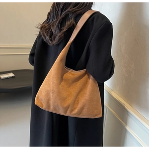 Gros plan d'un sac porté épaule en daim caramel montrant la texture douce et les bords