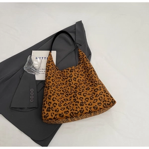 Sac fourre-tout à imprimé léopard avec poignées noires à côté d'un blazer gris chic