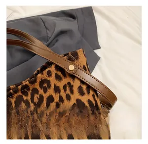 Detail show of golden rivet fastening brown leather strap to leopard print suede bag