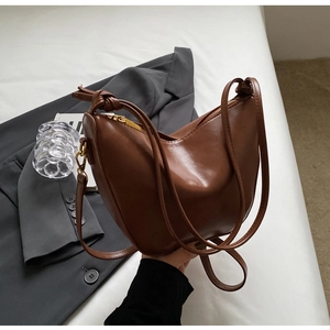 Detailed texture of retro brown faux leather hobo bag with gold zipper bag with knot strap on grey suit