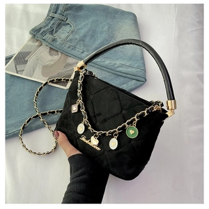 Detailed view of black quilted handbag with heart charms and gold chain shoulder strap