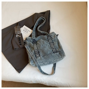 Detail of adjustable strap and silver metal buckle on washed blue denim tote bag