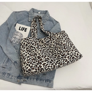 Detailed top view of a large leopard print tote bag with double handles on a neutral surface