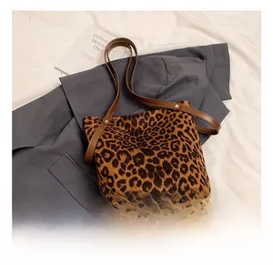Detail of leopard print suede bucket bag featuring brown leather strap and gold hardware