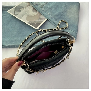 Detail view of black quilted handbag showing purple lining and internal storage pocket