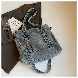 Detail of vintage washed blue denim tote bag with adjustable straps on aesthetic background