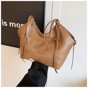 Close-up of brown faux leather tote bag showing double straps and adjustable metal buckle