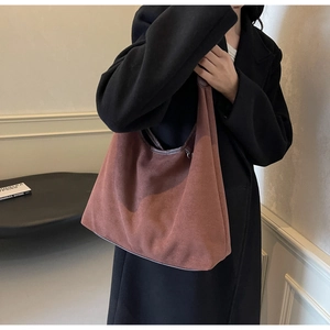 Détail macro du sac cabas en daim marron rouge foncé avec texture élégante et drapé