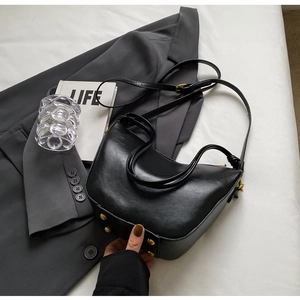 Detail of black crescent bucket bag with gold rivets and adjustable leather strap