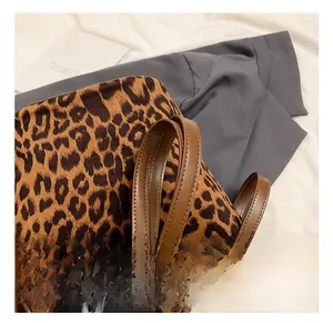 Detailed close-up of leopard print tote bag handle with dark brown leather and metal rivets
