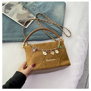 Detail of brown suede crossbody bag with gold chain strap and colorful enamel heart charms