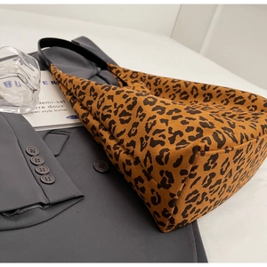 Détail d'un sac cabas imprimé léopard sur un blazer gris avec des accessoires de mode