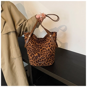 Close-up of leopard print faux fur bucket bag with leather handles and gold brand text