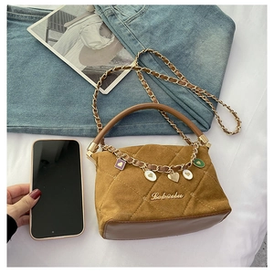 Detail of mini brown quilted suede handbag with gold Lebailu logo and heart charms