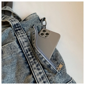 Detail view of denim tote bag side pocket with metal zipper and phone storage