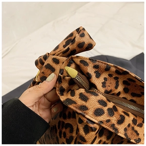 Close-up of leopard print bag featuring gold zipper and bow-shaped handle detail