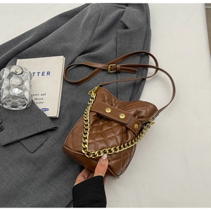Macro shot of brown quilted bucket bag with gold chain and refined leather texture