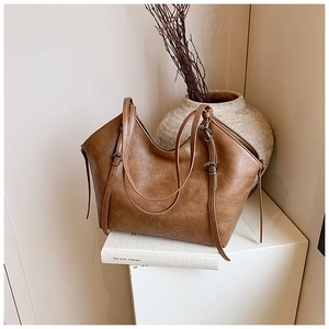 Detail view of the deep brown leather texture and elegant tassel on this tote bag