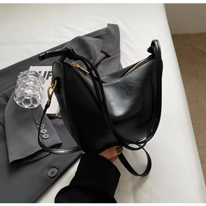 Detail view of the sleek black crescent leather bag with premium gold hardware accents