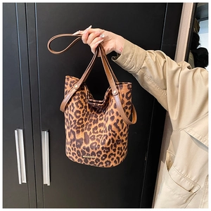 Detailed view of leopard print bucket bag with brown leather handles and gold logo branding