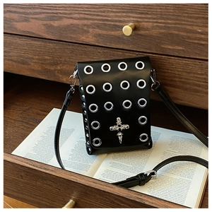 Close-up of black leather crossbody bag with silver eyelets and gothic cross detail