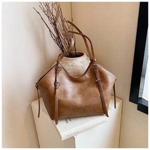 Detailed view of the vintage brown tote bag texture and adjustable silver buckle straps