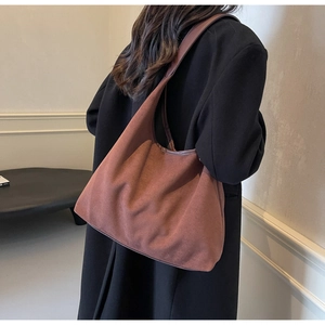 Vue détaillée du sac hobo en daim marron porté par un mannequin en manteau noir