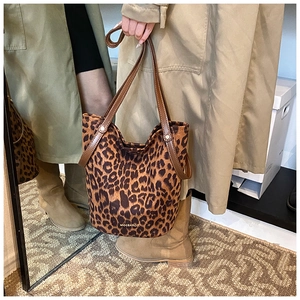 Close-up of leopard print bucket bag with brown leather strap and brand logo detail