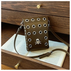 Detail of vintage punk crossbody bag with silver eyelets and metal skull clasp