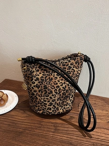 Leopard print tote bag with black rope straps and golden flower charm on wooden table