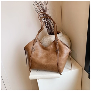 Close-up of vintage brown leather tote bag texture with silver buckles and thin straps