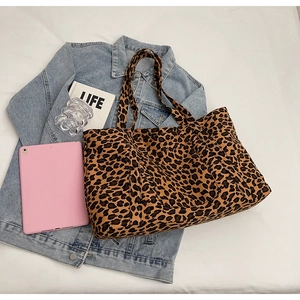 Detail of spacious leopard print tote bag placed on denim jacket with a tablet