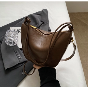 Detail of retro dark brown bucket bag with unique knotted strap and gold zipper finish