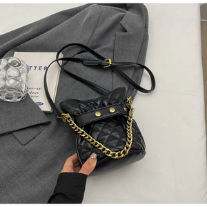 Detailed close-up of quilted black bucket bag with gold chain and cat-ear design details