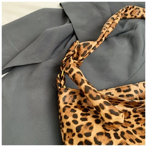 Close-up of leopard print canvas bag featuring gold metal rings and knotted strap details